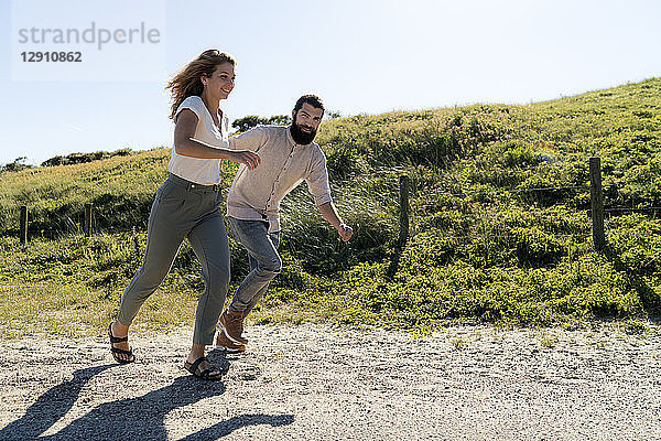 Young couple having fun in the dunes  running hand in hand