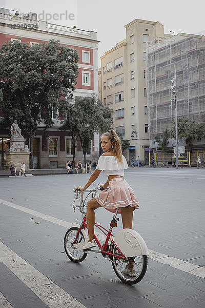 Fashionable young woman exploring Barcelona with a bicycle