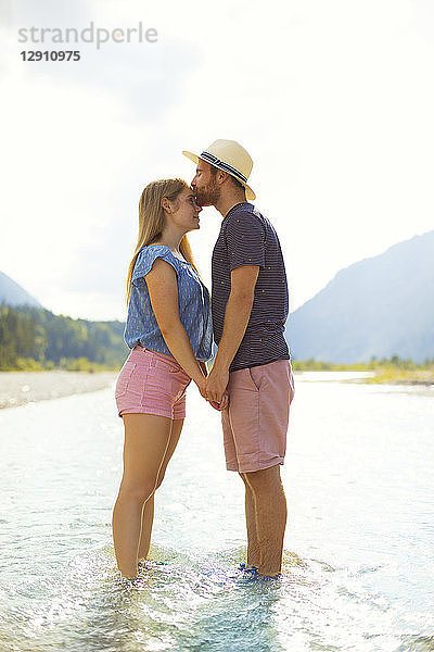 Young couple standing in water  kissing
