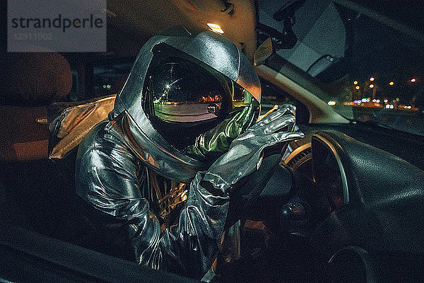 Spaceman sitting in car at night