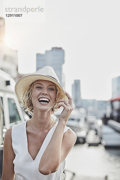 Portrait of laughing young woman wearing a hat at a marina