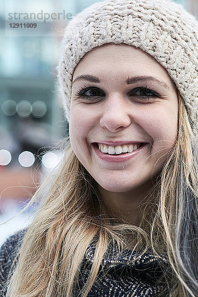 Portrait of smiling blond young woman wearing wool cap in winter