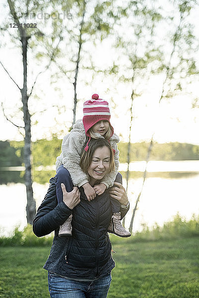 Finland  Kuopio  mother carrying daughter piggyback at a lake