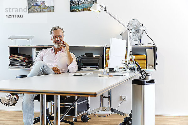 Portrait of smiling businessman sitting at desk in office