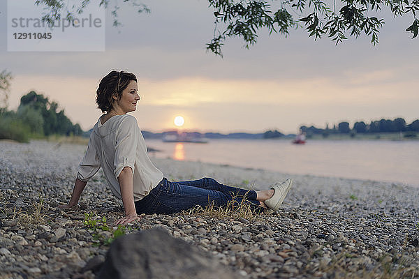Woman sitting at the river  watching sunset