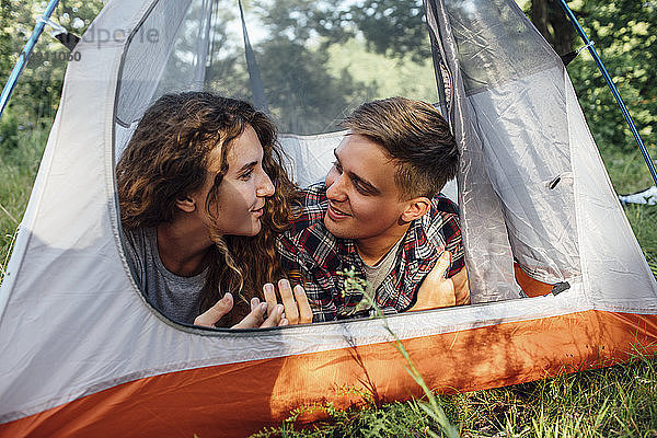 Happy young couple lying in tent  talking