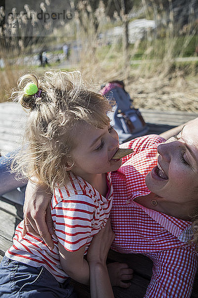 Happy mother and daughter with ice cream cone on a jetty