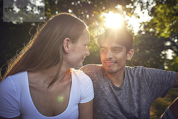 Romantic young couple sitting in park  enjoying sunset