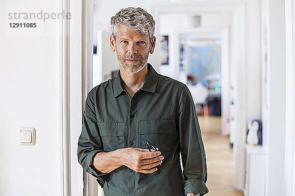 Portrait of mature man with grey hair and stubble at home