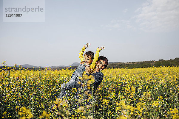 Spain  portrait of happy mother and her little son up standing in rape field
