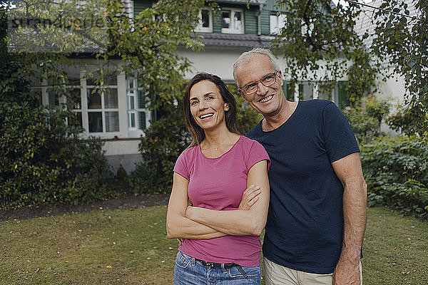 Happy mature couple standing in garden of their home