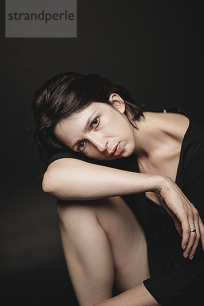 Portrait of sad woman sitting in front of black background