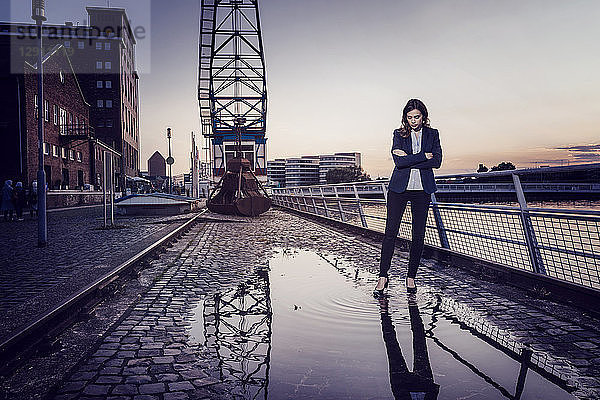 Businesswoman standing at wet inner harbor  thinking