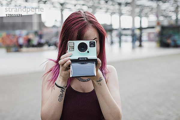 Young woman taking photo with instant camera outdoors