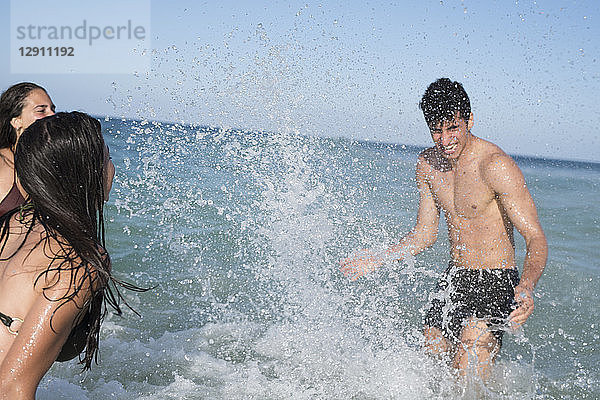 Happy carefree friends splashing in the sea