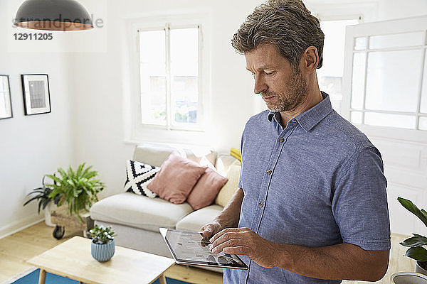 Mature man at home using digital tablet