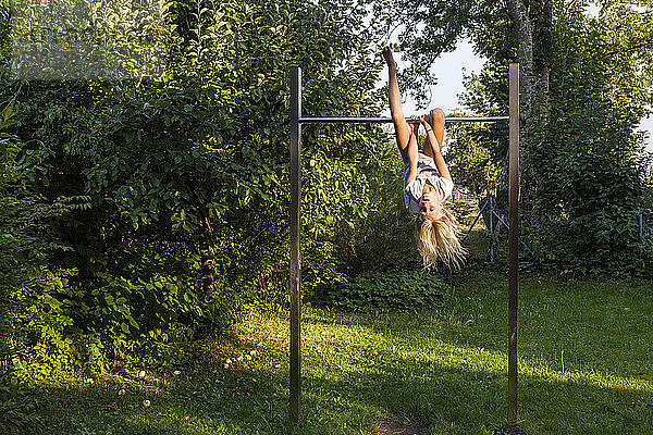 Girl exercising on gymnastics bar in garden