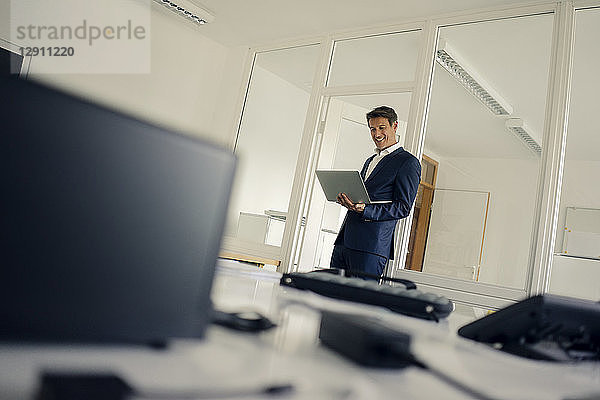 Businessman standing in office  using laptop