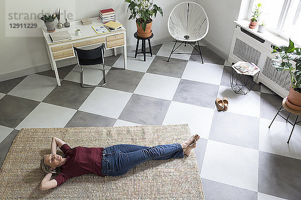Relaxed mature woman lying on the floor at home