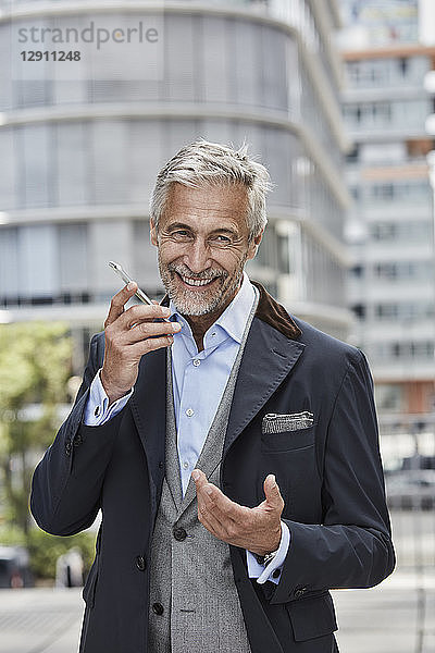 Germany  Duesseldorf  portrait of laughing mature businessman talking on mobile phone