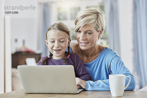 Mother and daughter using laptop at home