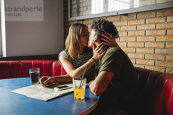 Young couple with map kissing in a cafe