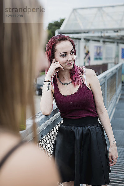 Smiling young woman with dyed hair standing on footbridge