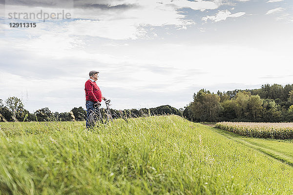 Senior man with bicycle in rural landscape