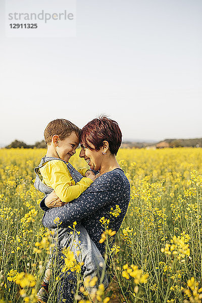 Mother standing with her little son in a rape field