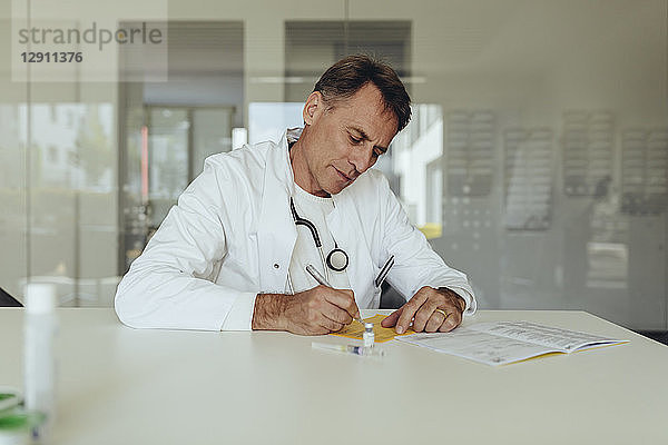 Doctor sitting in practice  filling in immunization card