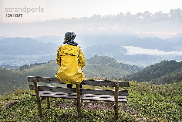 Austria  Tyrol  Fieberbrunn  Wildseeloder  woman sitting on bench with view on mountainscape