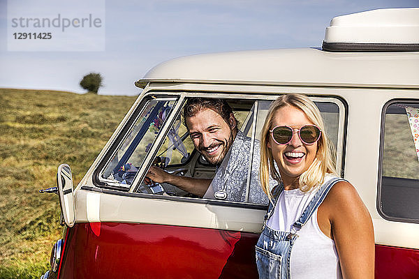 Happy couple with van in rural landscape