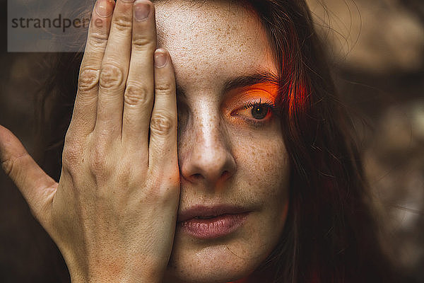 Portrait of young woman with freckles covering one eye
