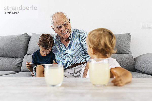 Portrait of grandfather spending time with his grandson and granddaughter