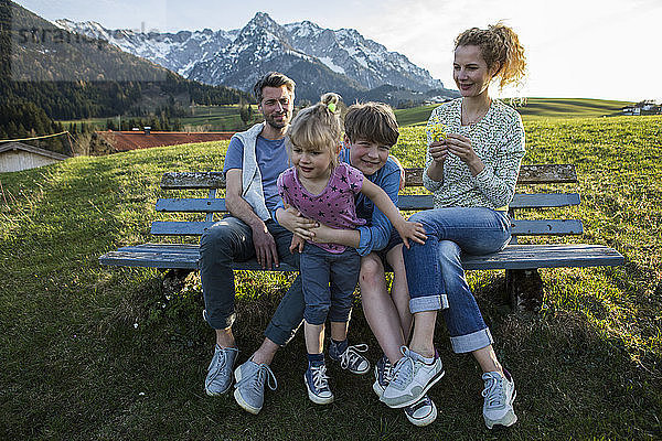 Austria  Tyrol  Walchsee  happy family resting on a bench in the mountains