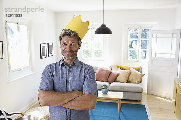 Mature man at home wearing paper crown  looking content