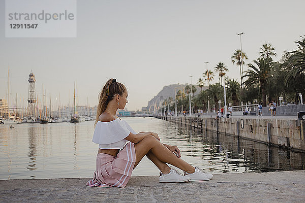 Fashionable young woman sitting at the harbour of Barcelona  Spain