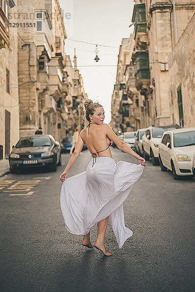 Teenage girl weraing long skirt and bikini top  posing in the street