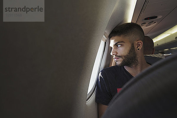 Young man in a plane looking out of window