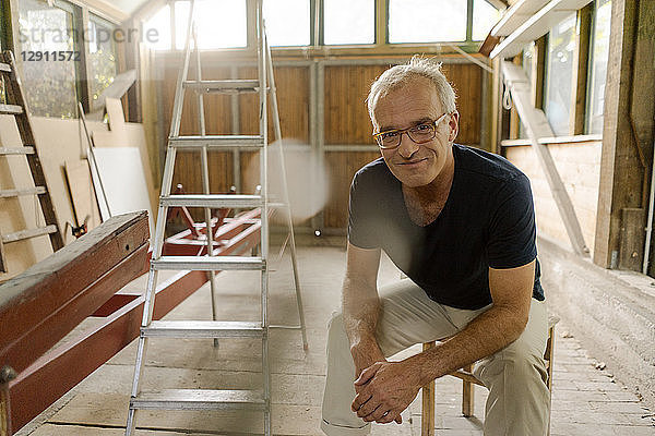 Portrait of a confident mature man sitting in his workshop