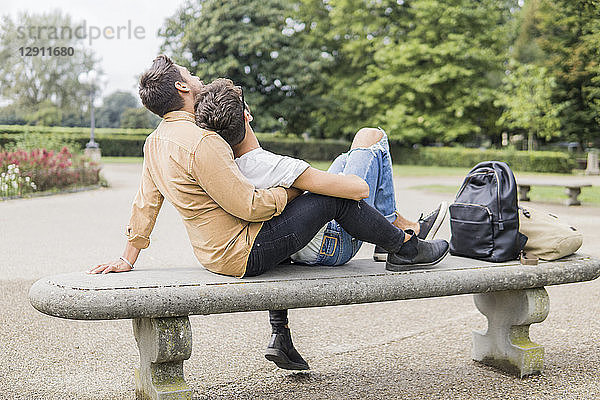 Young gay couple relaxing together on bench