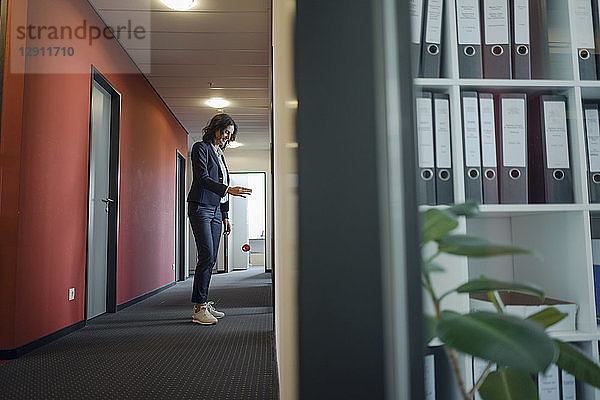 Mature businesswoman standing in office corridor  playing with yoyo