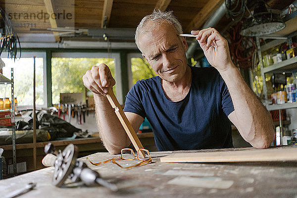 Mature man at workbench in his workshop thinking