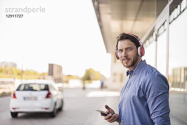 Smiling man listening to music with headphones outdoors