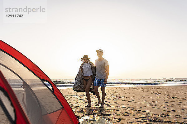 Romantic couple camping on the beach  doing a beach stroll at sunset
