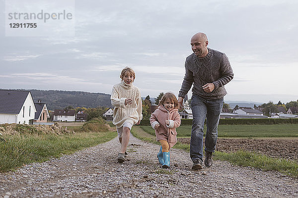 Father with two children running on field path