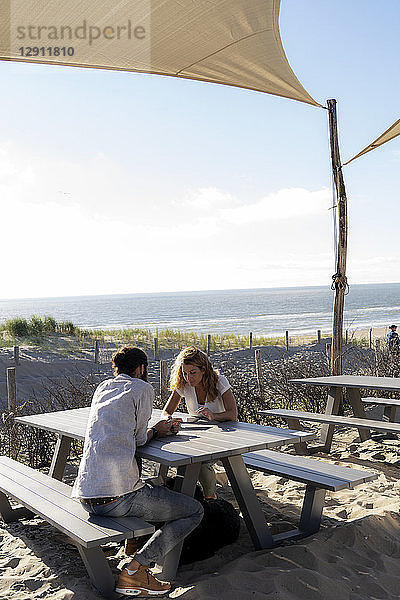 Young couple using digital tablet  sitting a ta a table at the beach