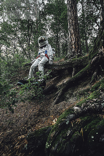 Spaceman exploring nature  sitting on tree roots