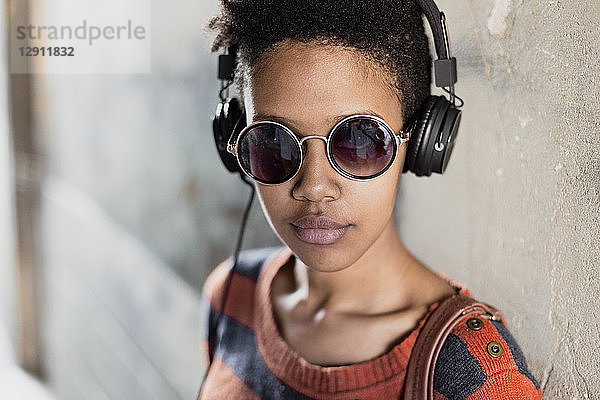 Portrait of young woman wearing sunglasses listening music with headphones