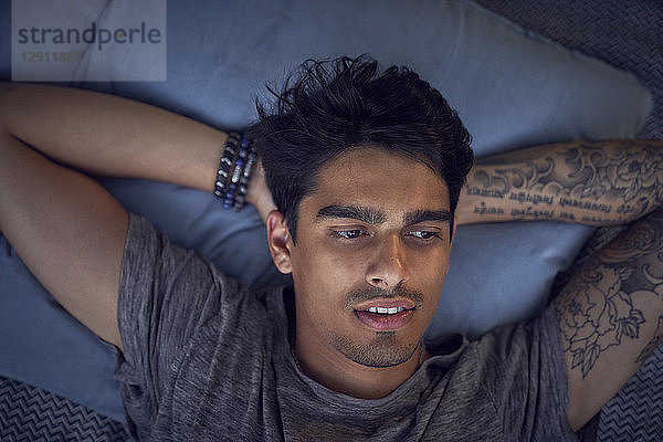 Young man with tattoo  relaxing on cushion